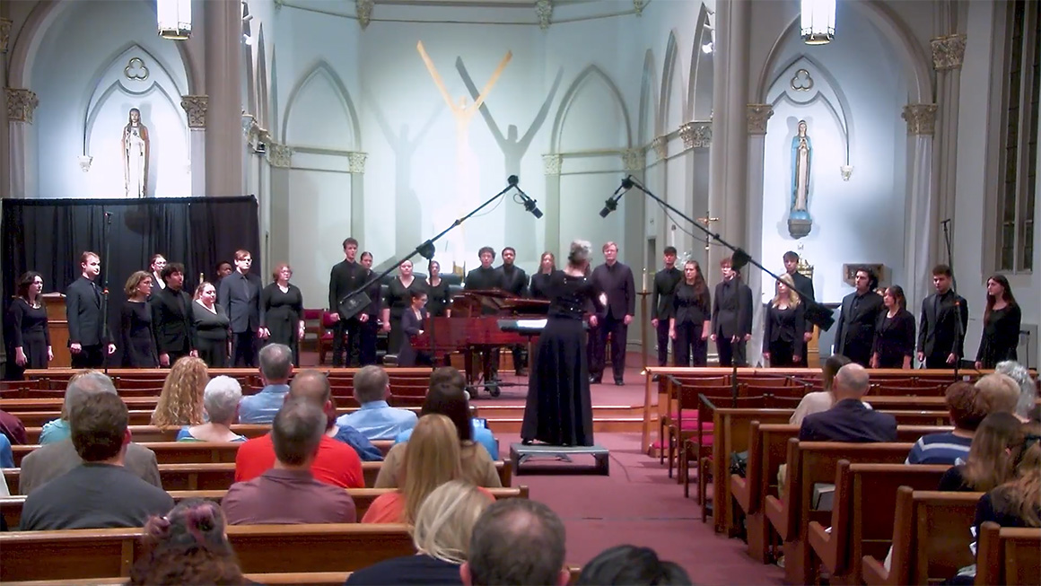 A choir performs on the alter of the Chapel of the Holy Spirit at Duquesne University. An audience can be seen in the foreground.
