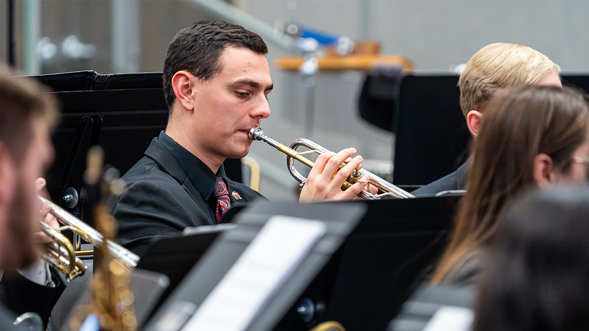 Trumpet player performs seated within ensemble during live concert.