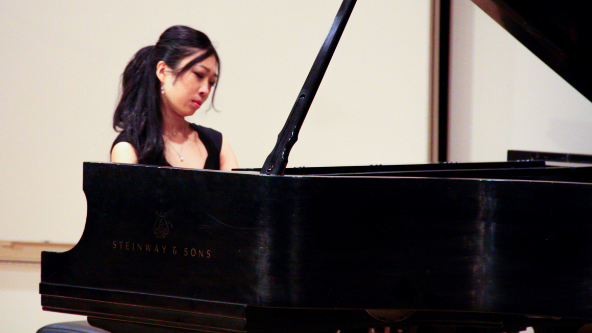 A person with long hair plays a Steinway piano.