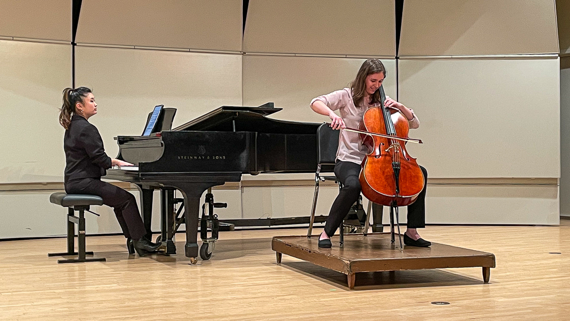 A cellist and pianist perform on stage.