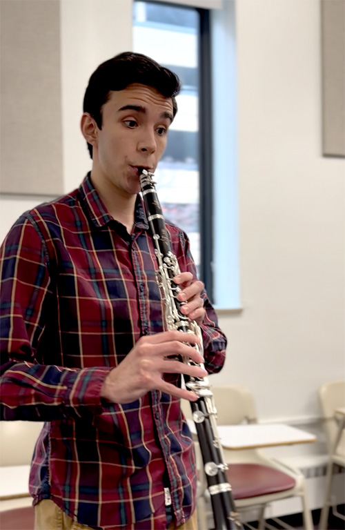 A person in a red checker shirt plays clarinet.