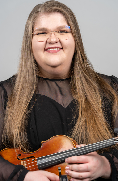 A violinist poses for a headshot.