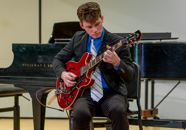 Student plays a guitar.