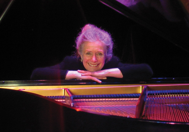 Pianist poses with a piano.