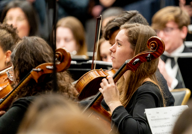 A girl playing cello smiles.