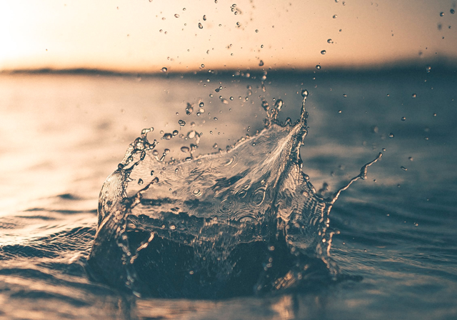 Splash in a body of water in front of a sunset.