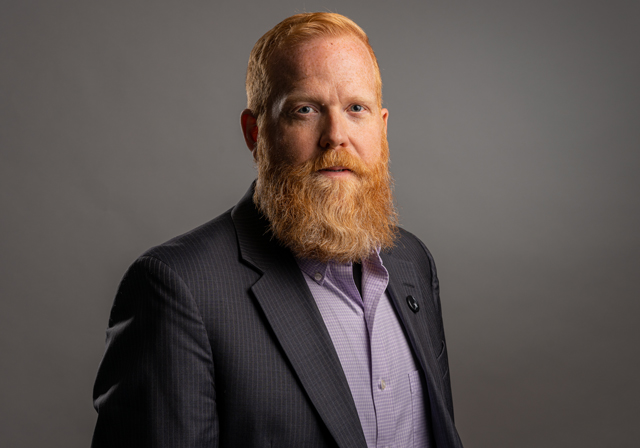 A man wearing a suit poses for a photo.