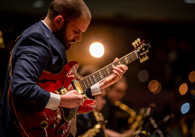 Student plays a guitar.