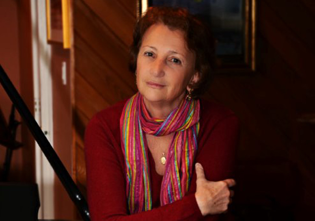 A person wearing a red shirt poses in a wood paneled room.
