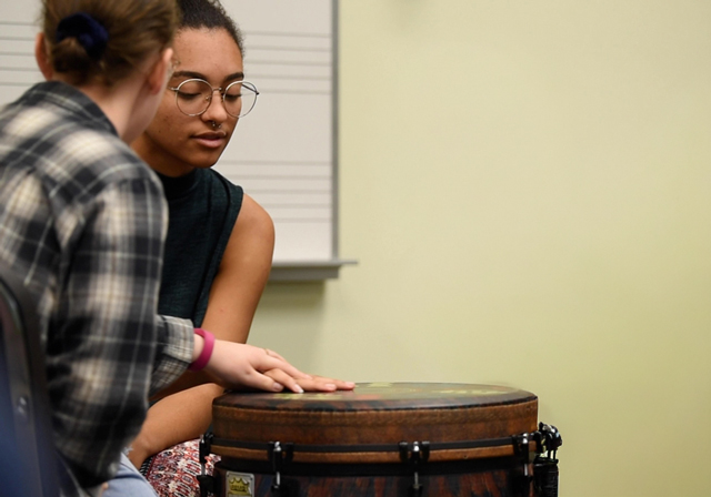 Two people play a drum together.