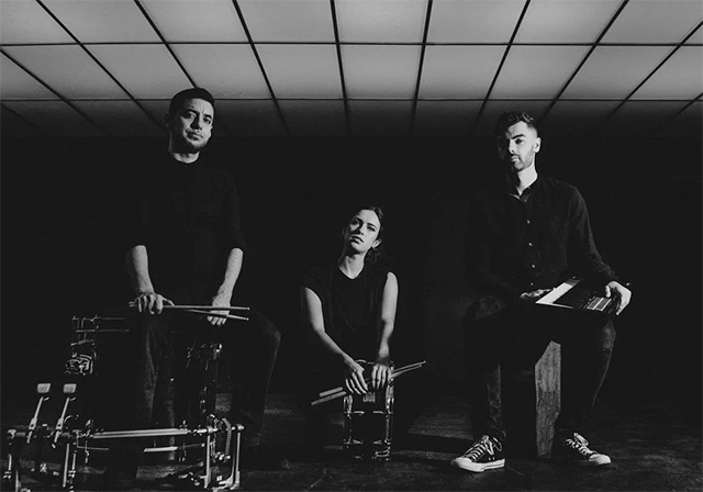 Black and white image of three people with drums and keyboards.