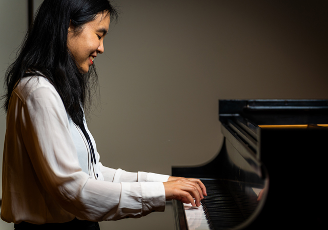 A person smiles while playing piano.