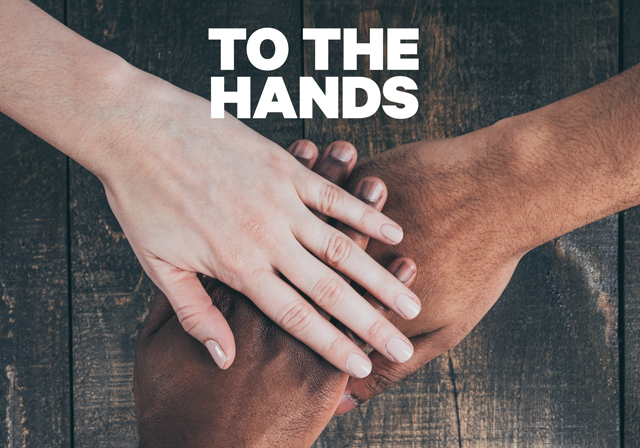 Three people join hands over a wooden background