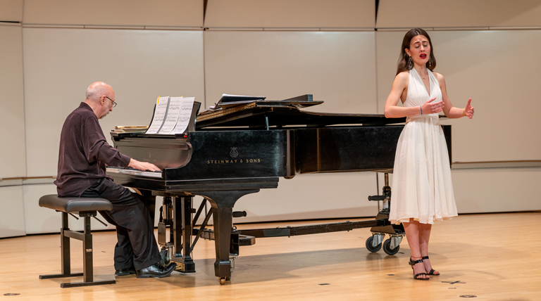 A singer performs with a pianist accompanying.