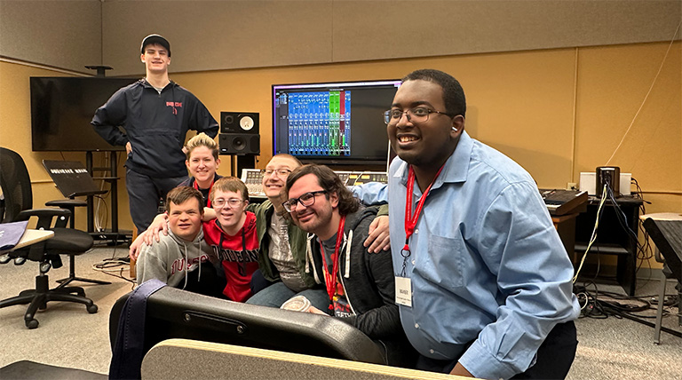 Seven people pose for a photo in a recording studio.
