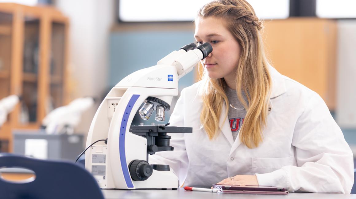 a girl looking in a microscope