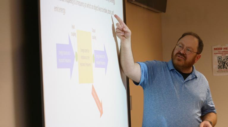 a teacher pointing at a whiteboard