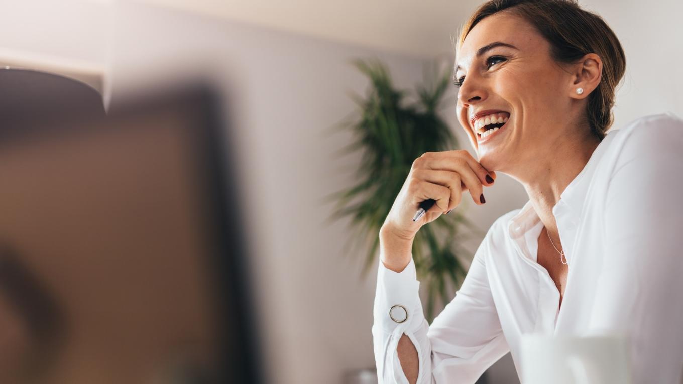 women laughing while looking beyond her computer