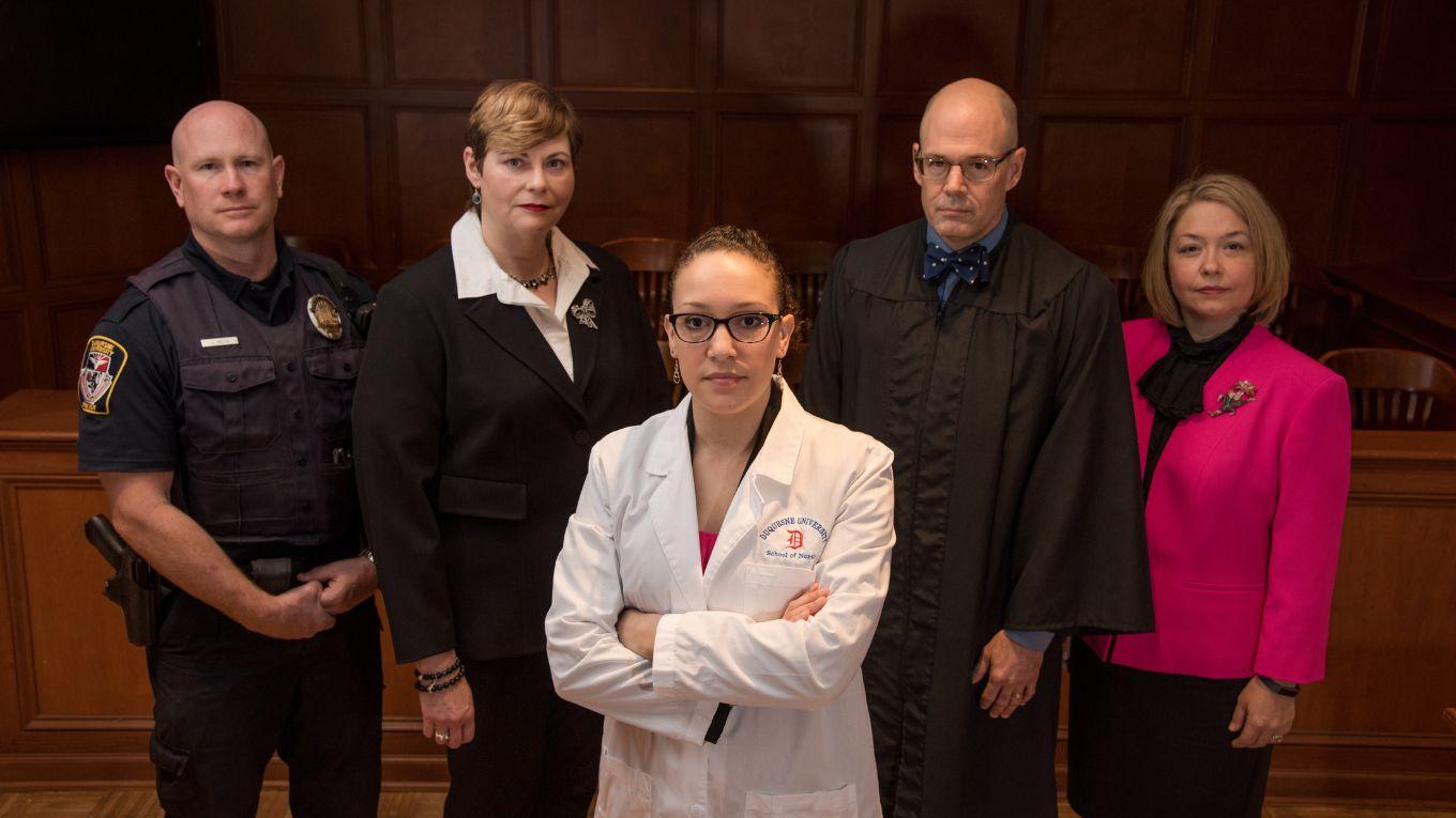 Group of nurses and court professionals standing in a court room.