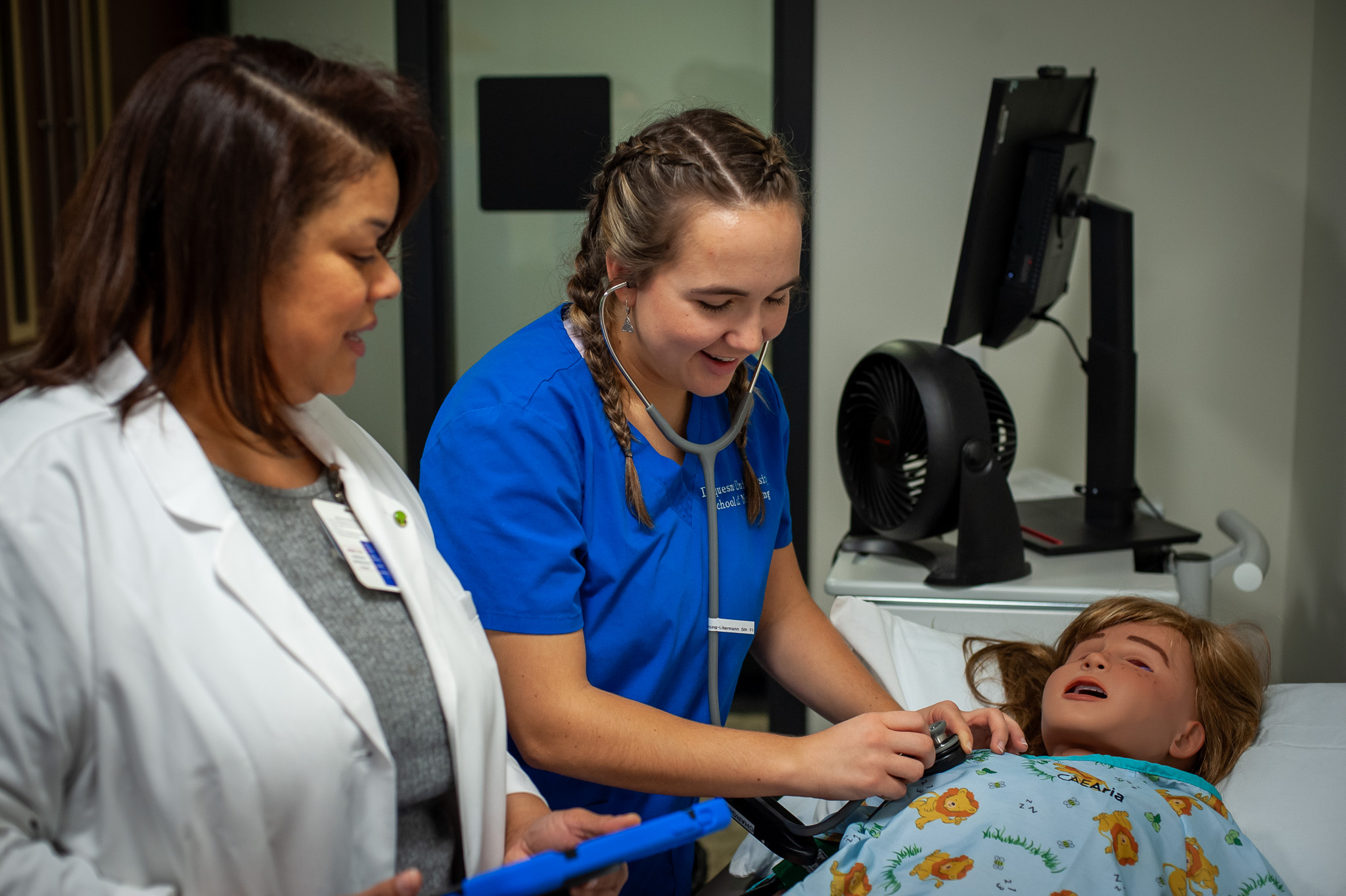 A nursing student practices on an educational mannequin.