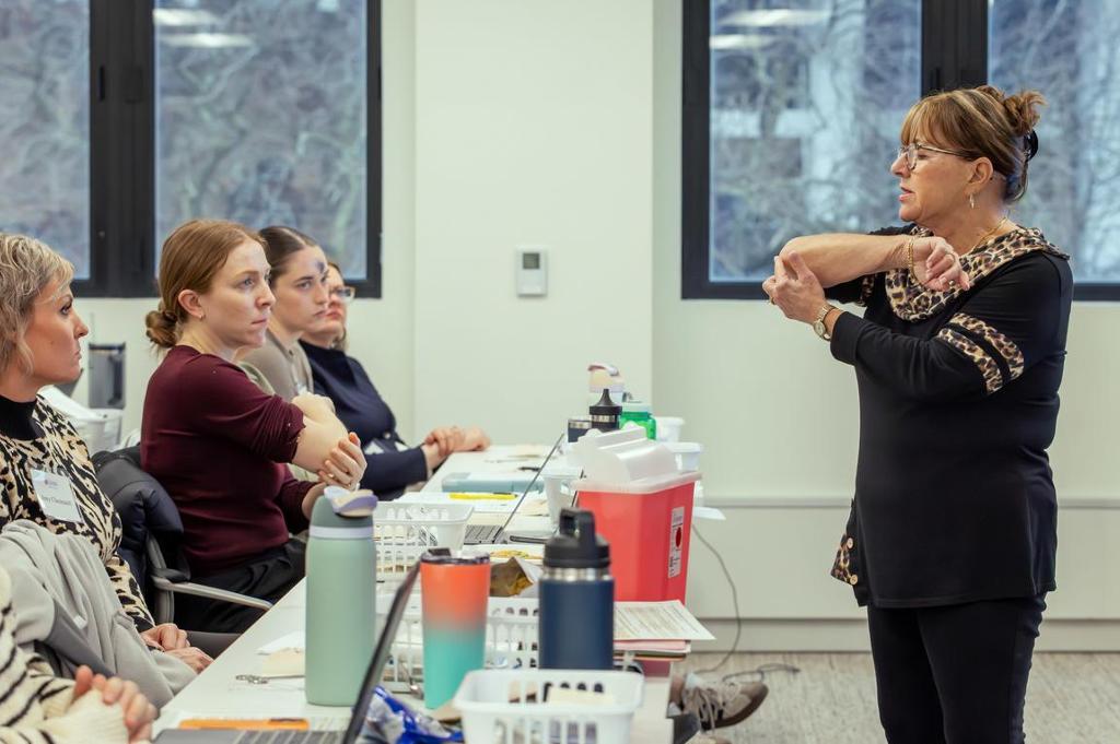 Teacher pointing at her elbow demonstrating in front of a class.
