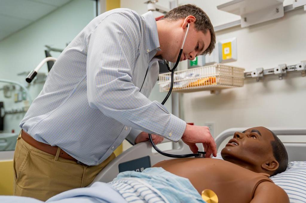 A man using a stethoscope on a nursing mannequin.