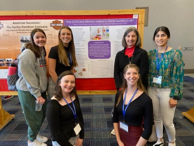 Team posing with their poster in the background