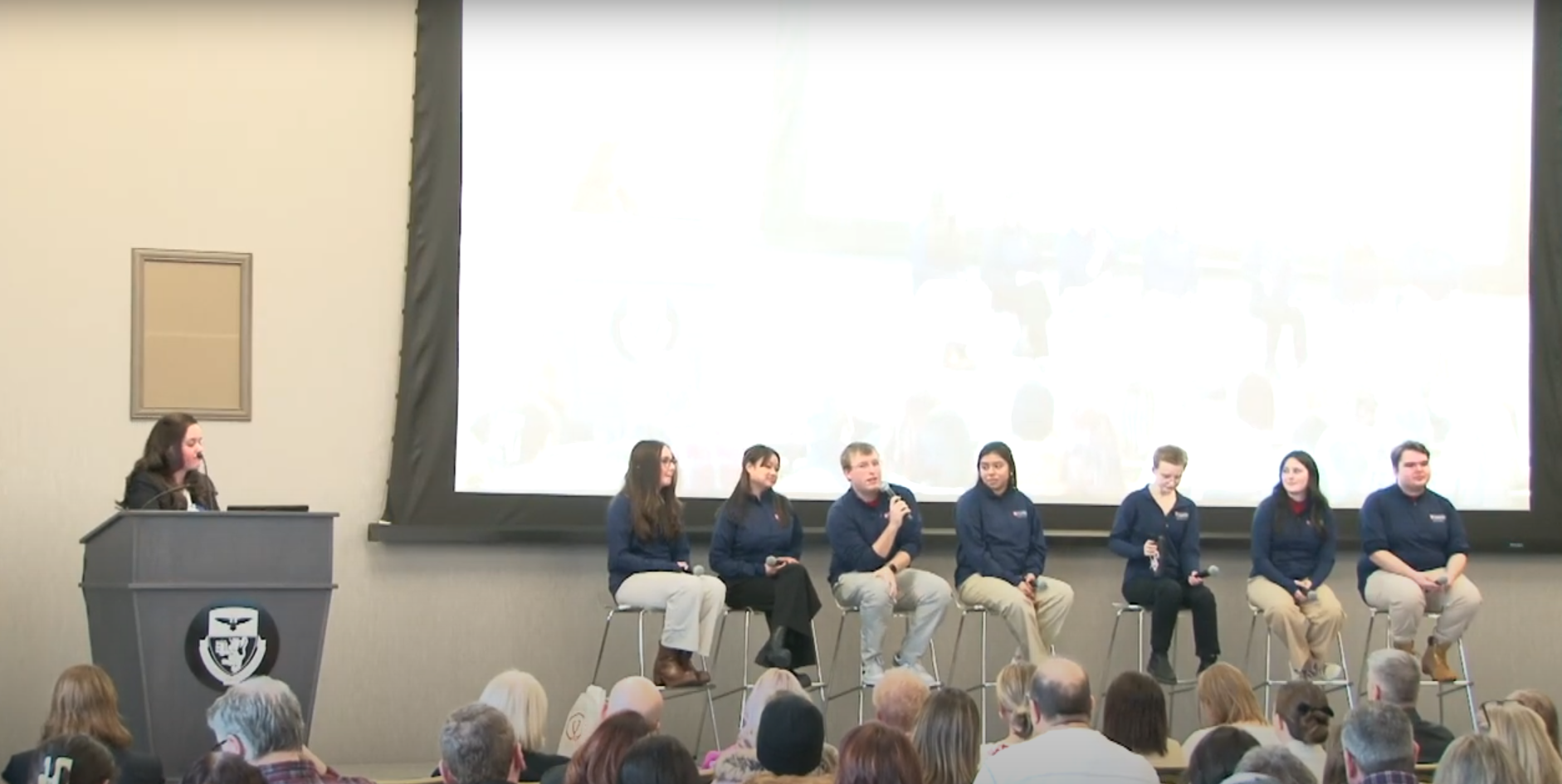 A group of students sit on a stage for a panel discussion. 