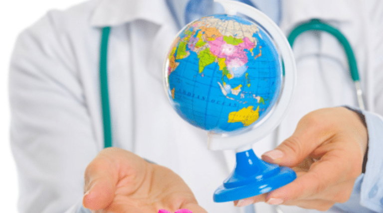 A person wearing a stethoscope holds a mini globe.