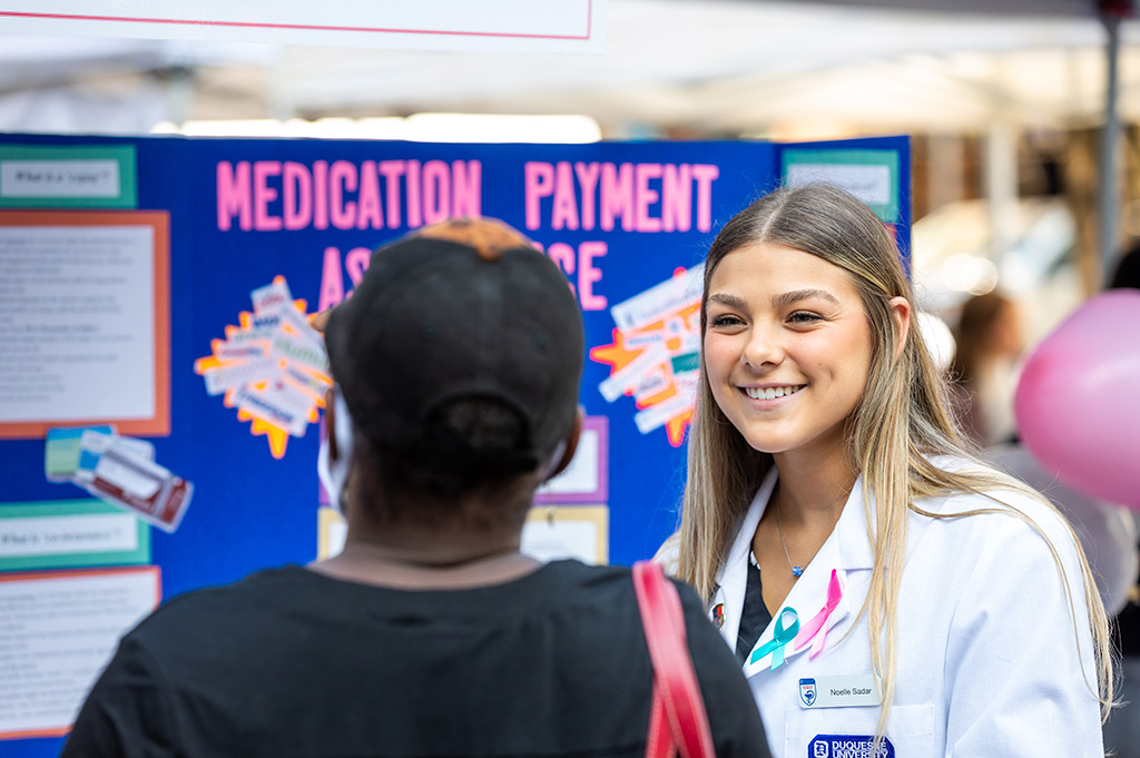 A student pharmacist talking to a community member at the Health and Wellness Fair