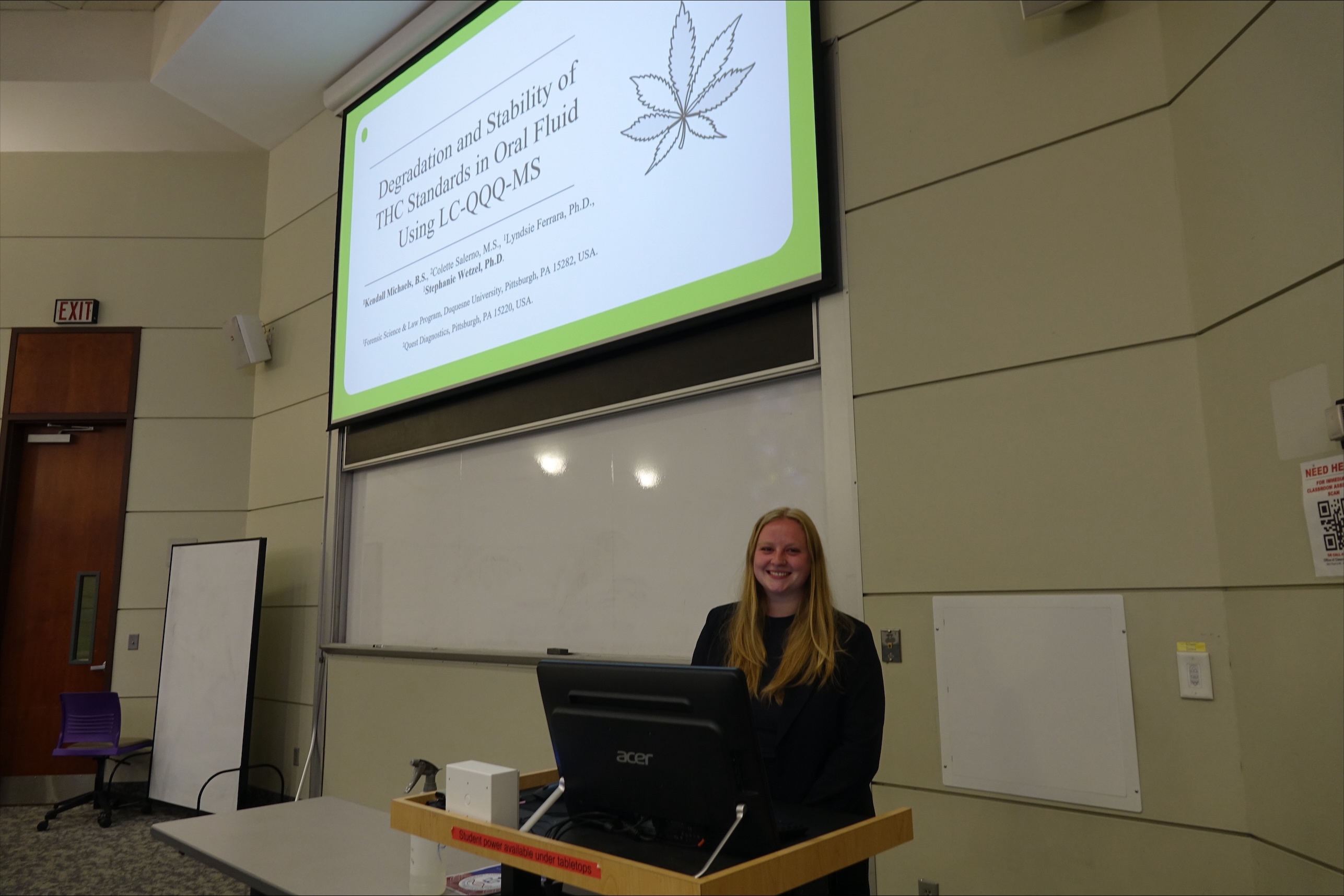 a female in a black shirt in front of a powerpoint presentation