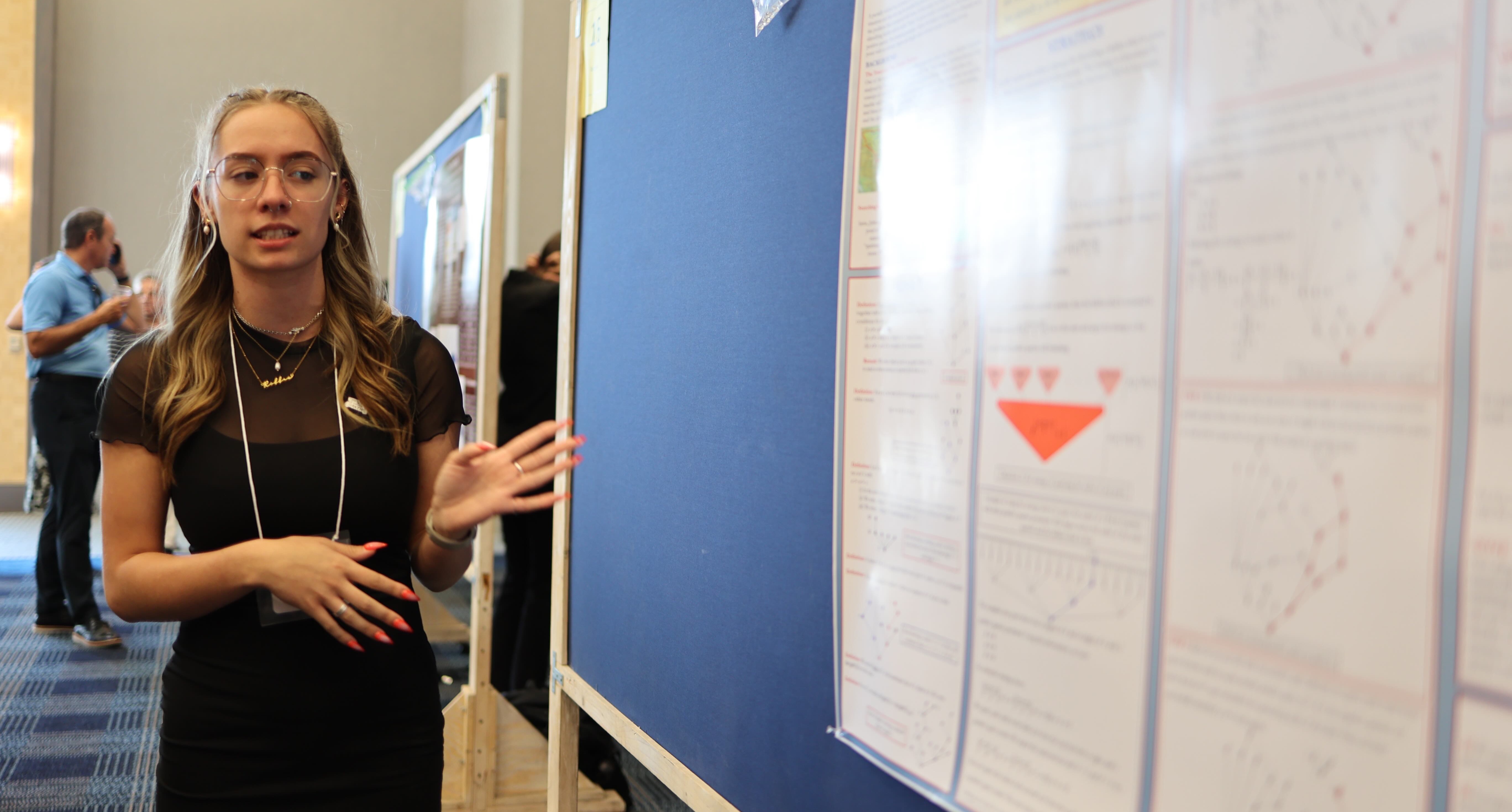 girl standing next to a poster
