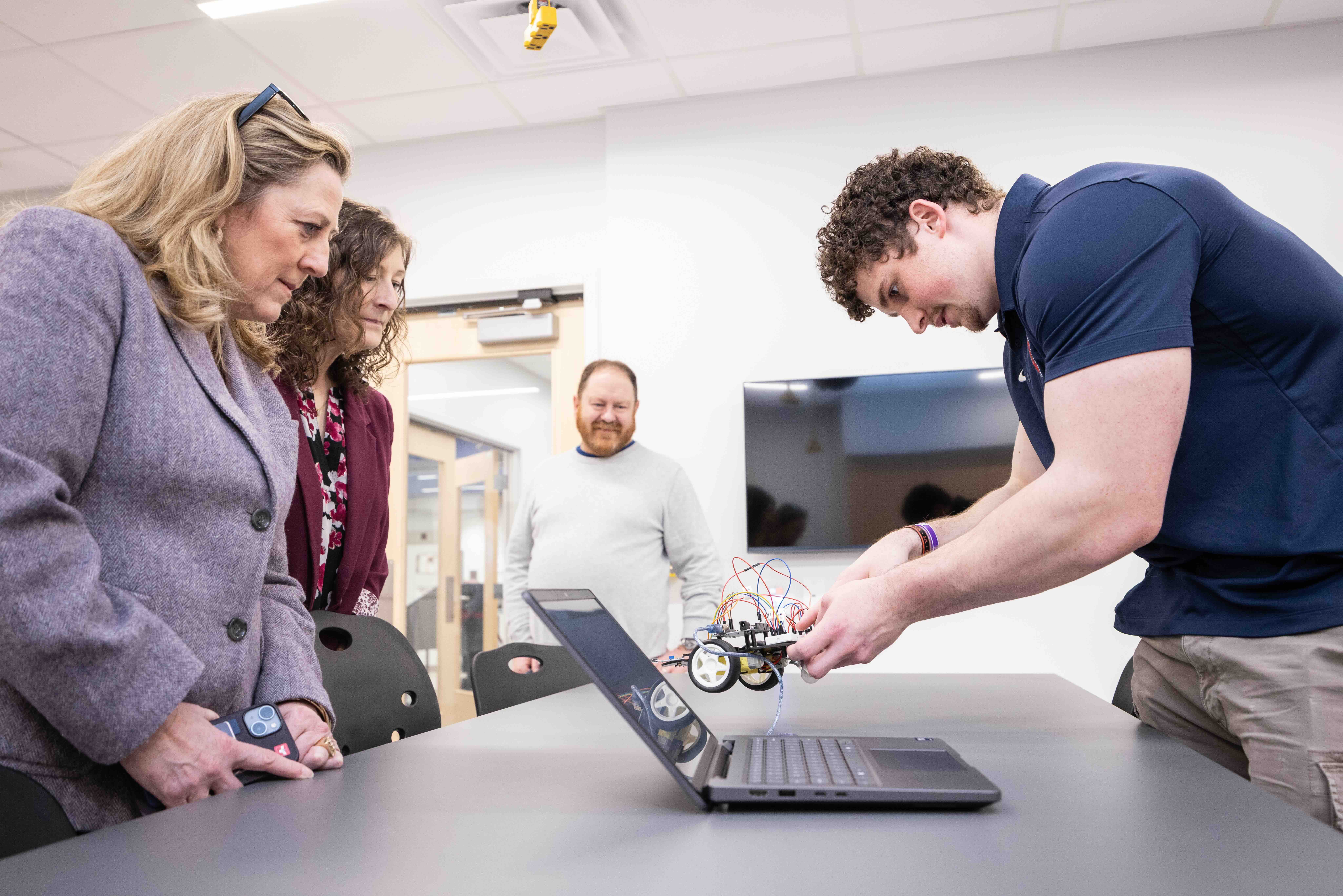 a male and two females looking at a piece of equipment