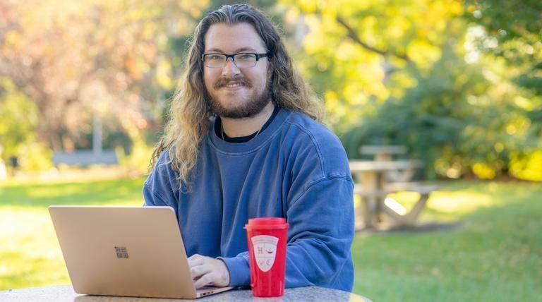Deagan Moore, an Endowed Honors Fellow, working on his laptop outside.