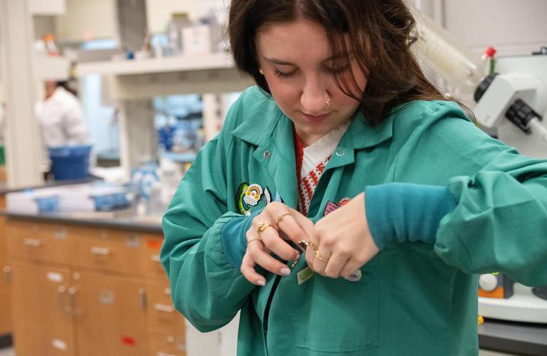 Alayna Funke adjusting her laboratory coat.