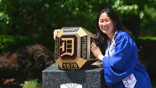 Joy Chen standing besides the Duquesne Ring on campus.