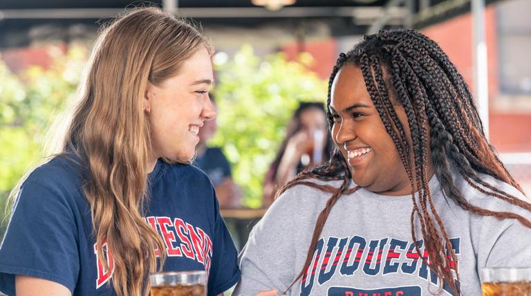 Two Duquesne students laughing with each other