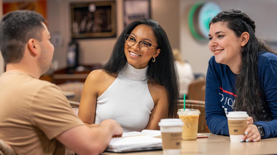 students having coffee together at a table on campus