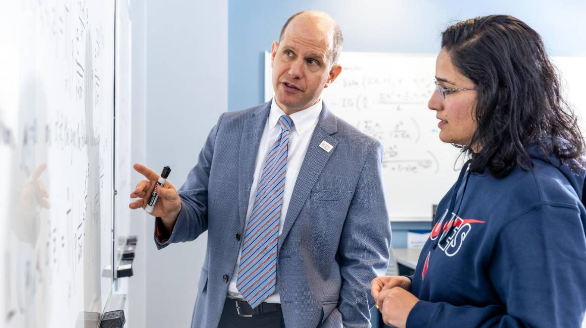 Professor helping student at a white board