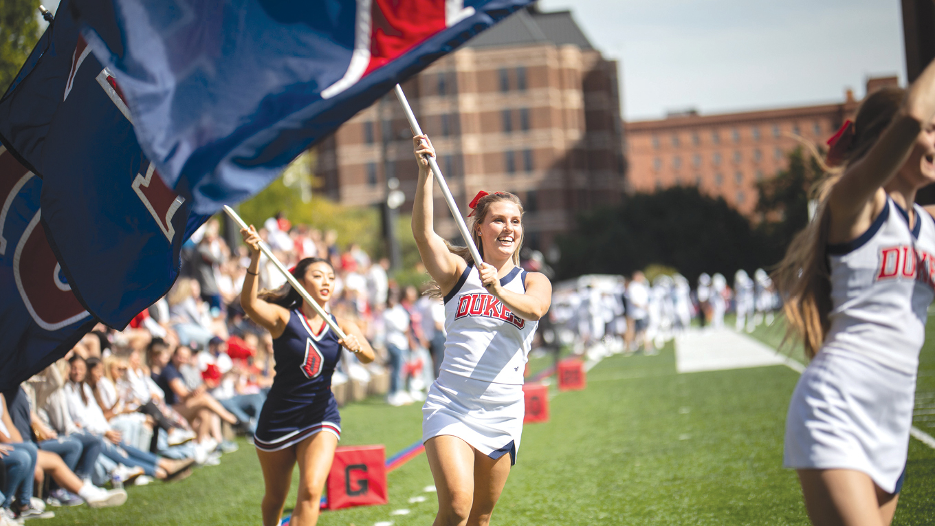 Cheerleaders waving Duquesne flags.