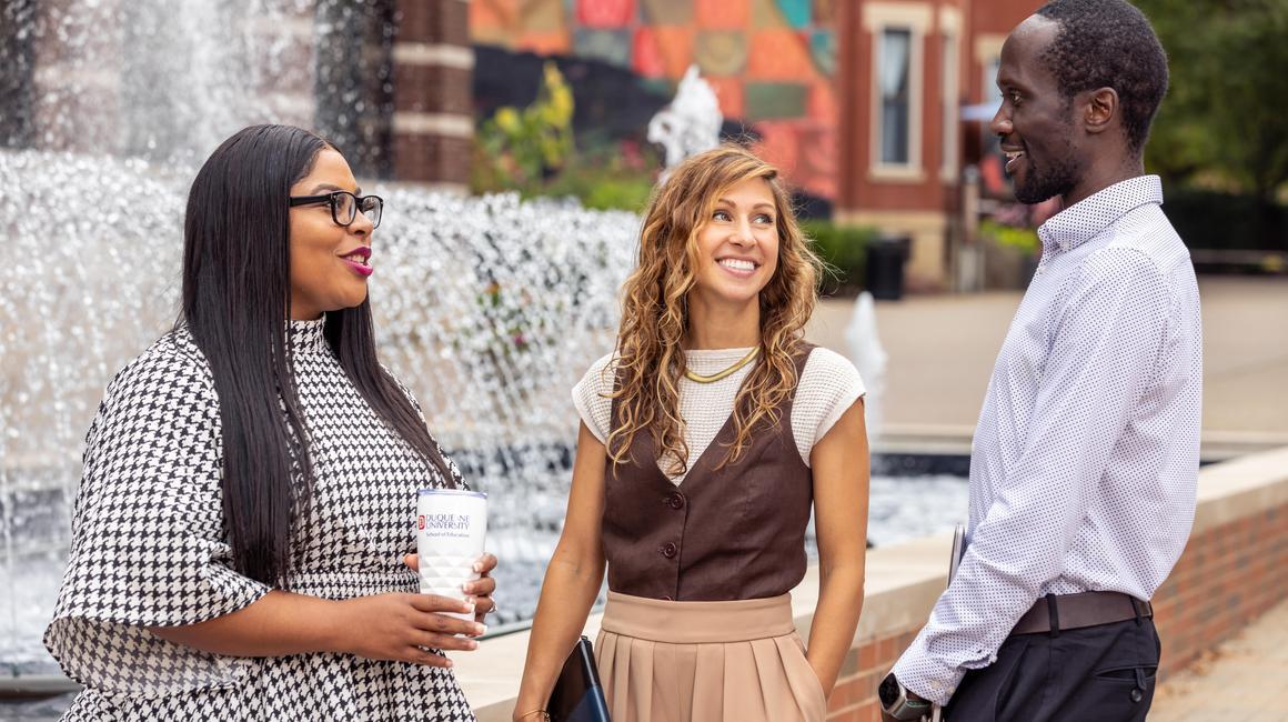 Duquesne graduate students talking on campus outside of Canevin Hall