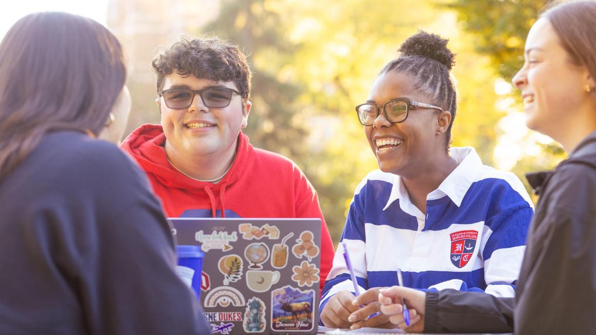 DU Honors College students outside chatting around a laptop