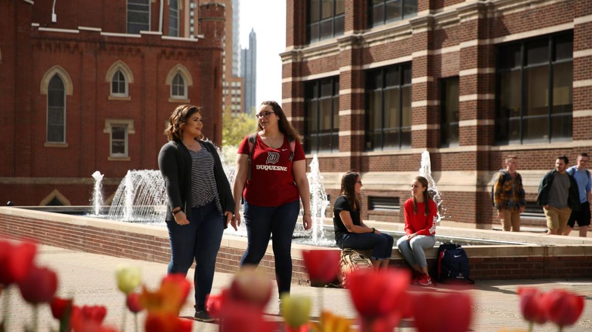 students walking on academic walk near fountain