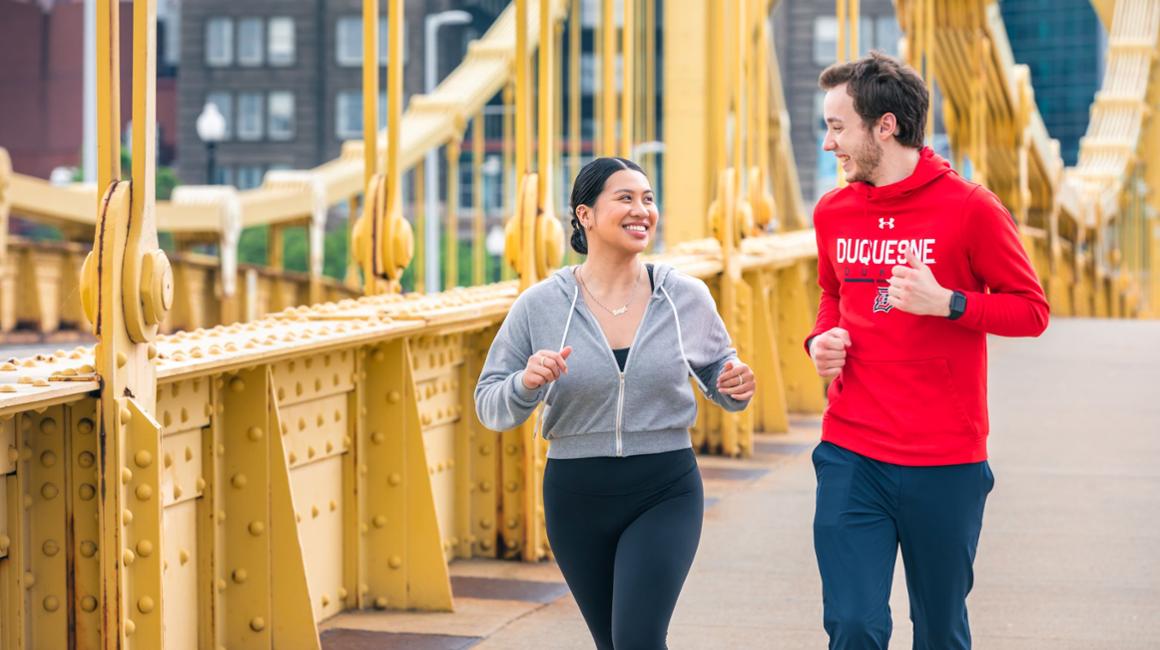 students runnin on Pittsburgh bridge