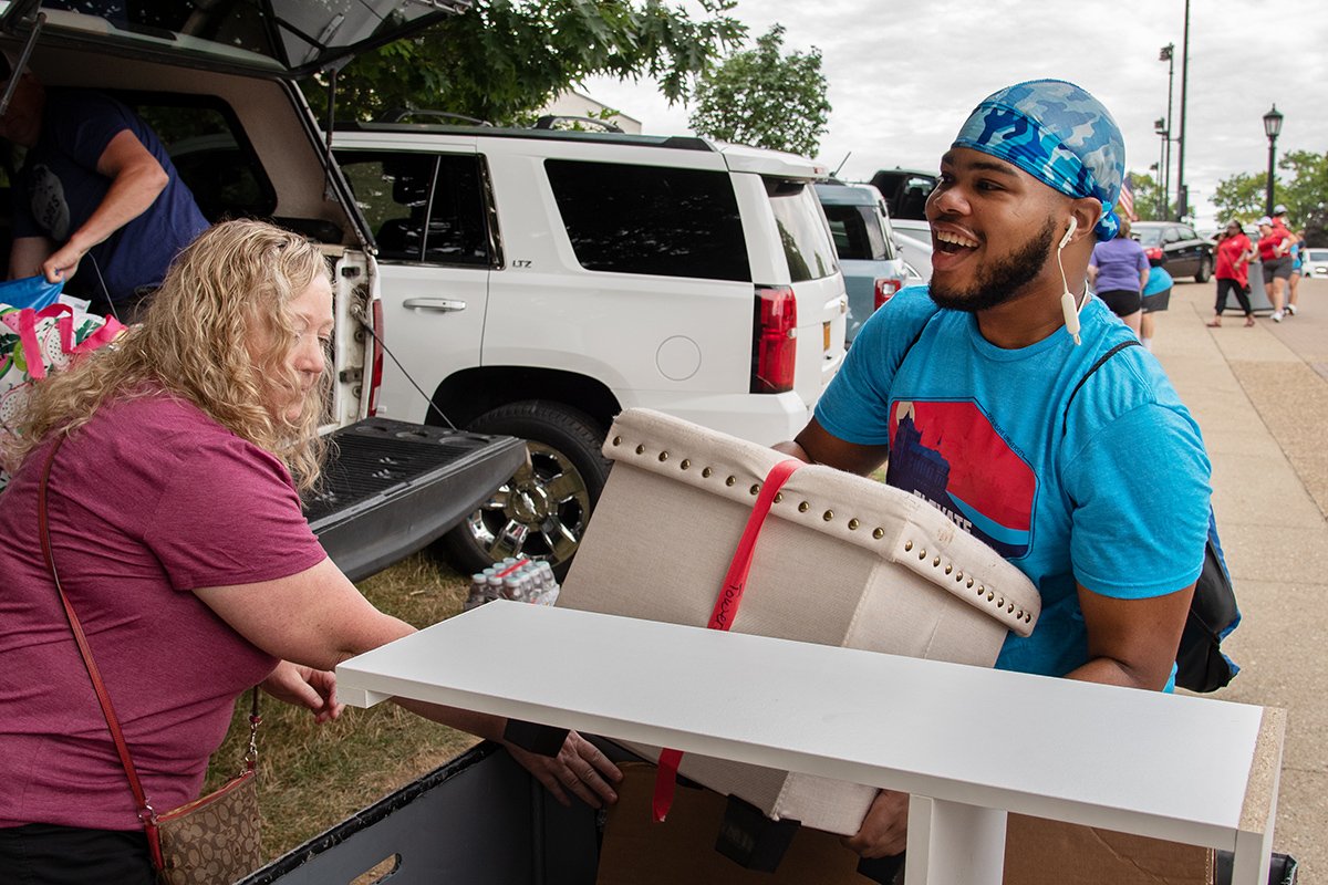A DU student volunteer loading a box in a cart.