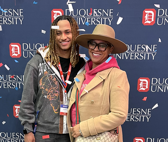 Admitted Duquesne student and his mom celebrating with confetti at a 2025 Admitted Student Day with Duquesne University logos in the background.