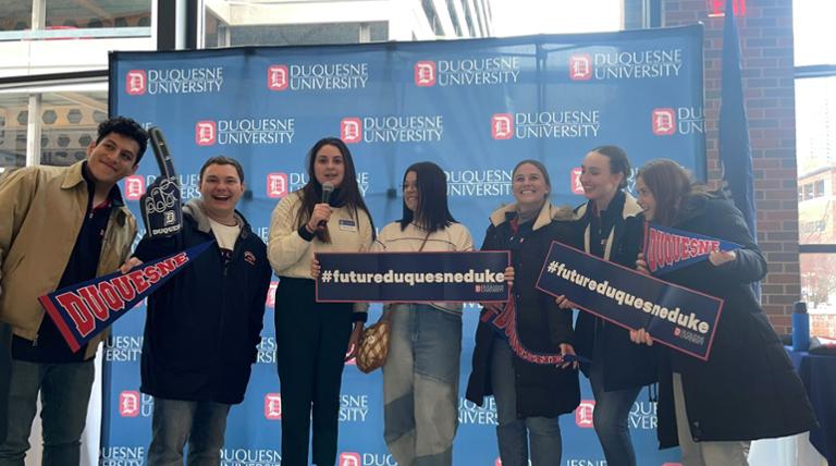 Admitted students celebrating at an admitted student event with signs that read FUTURE DUQUESNE DUKE