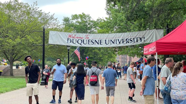 families exploring campus at an event under a WELCOME TO DUQUESNE UNIVERSITY BANNER