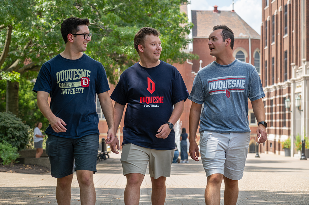 3 guys walking on academic walk.