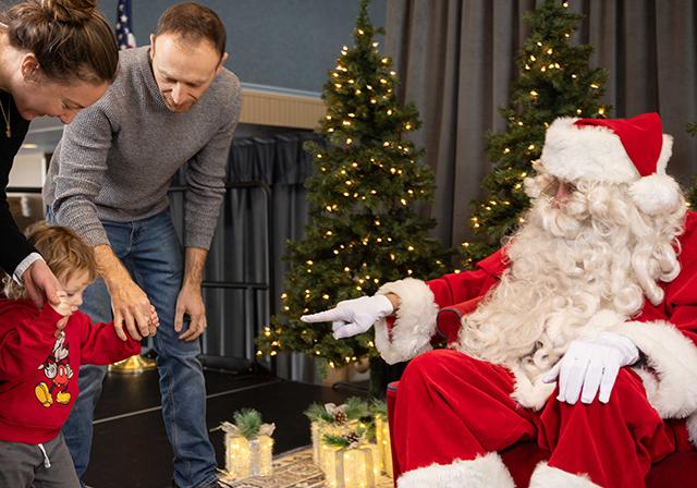 Santa greets child and parents.